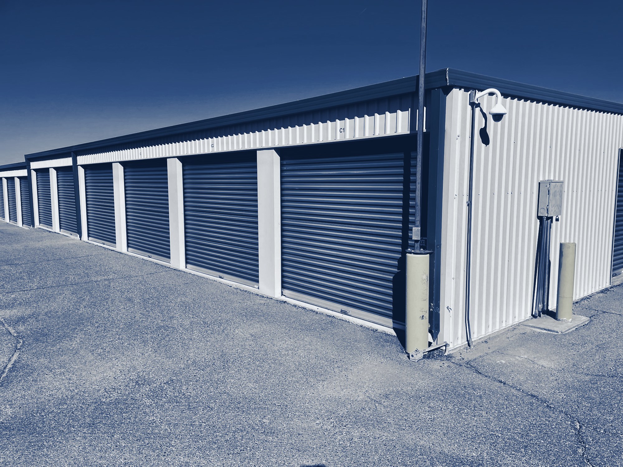 Row of self-storage units with roll-up doors, tinted navy