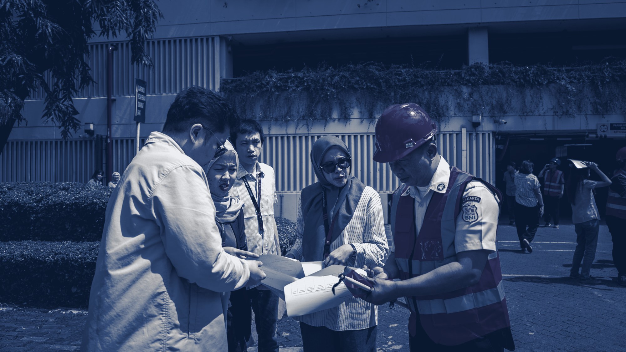 Project team reviewing plans on site, tinted navy