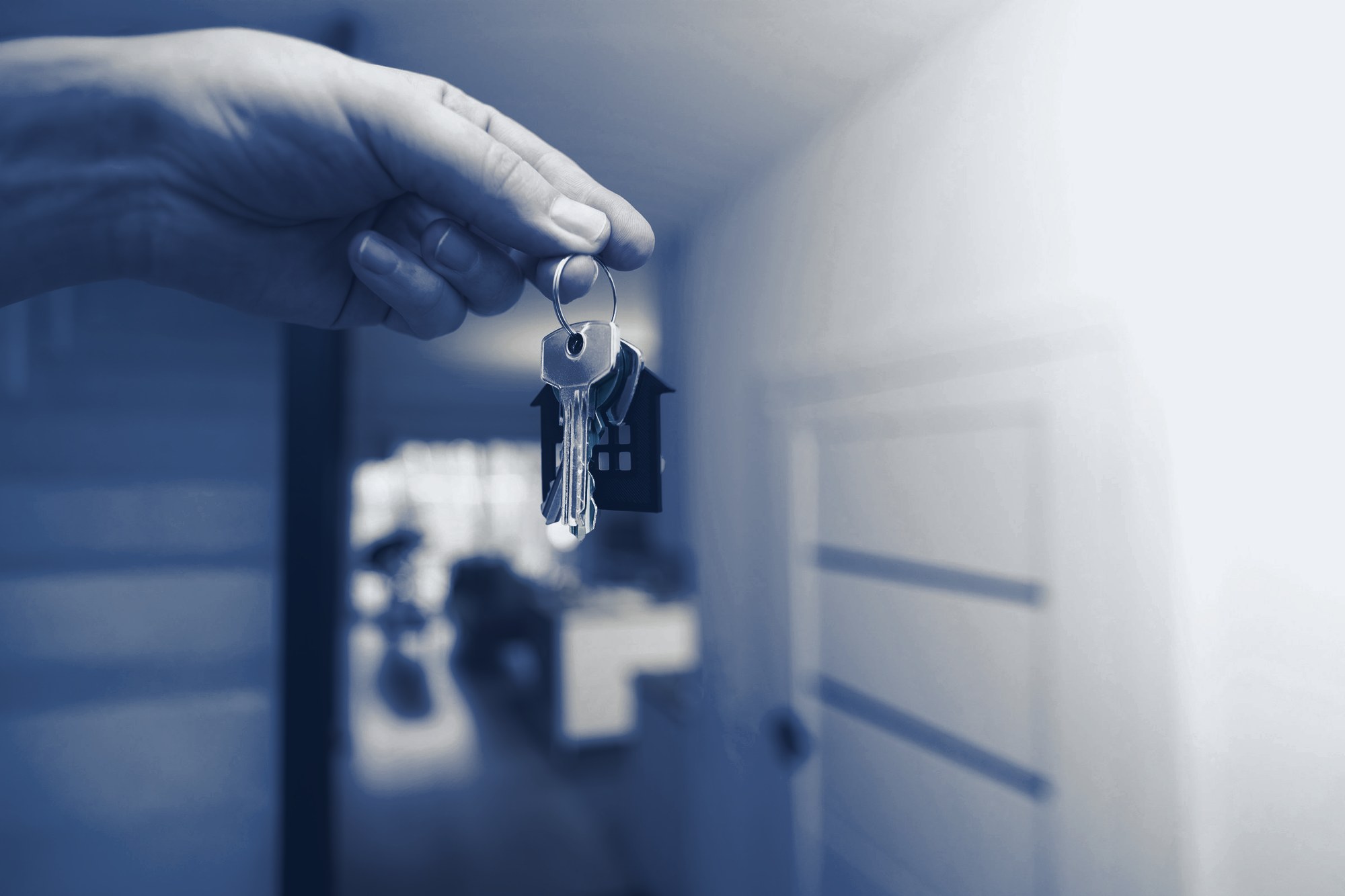 Keys handed over at an apartment door, tinted navy